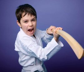 A Caucasian teenage boy in white kimono standing in fighting pose with wooden katana sword. Aikido fighter. Oriental martial arts concept