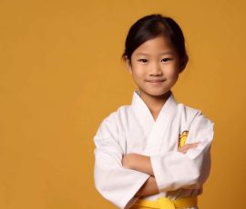 a smiling girl child dressed as a martial arts athletes in soft solid background generative ai